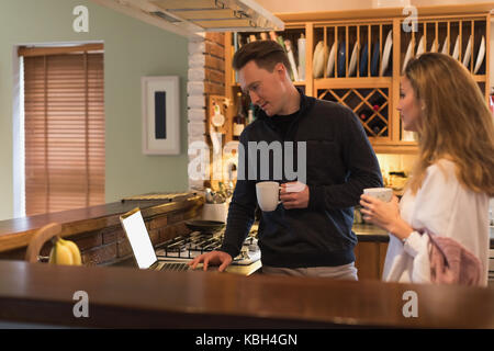 Couple using laptop in kitchen at home Stock Photo