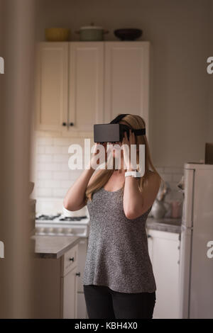 Young woman using virtual reality simulator in kitchen at home Stock Photo
