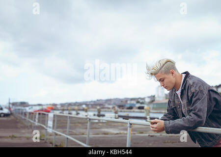 Man leaning on railing while using mobile phone Stock Photo