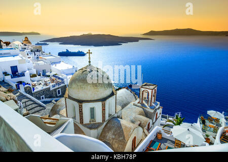 Fira, Santorini - Greek Islands landmark with white village, cobbled paths, greek orthodox blue church and sunset over caldera. Cyclades, Greece Stock Photo