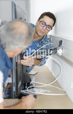 ethernet cable being plugged into a wall socket Stock Photo