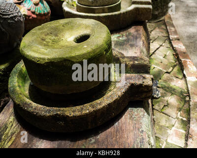 Ancient millstone have green lichen around and Ancient millstone put on old wooden boards Stock Photo