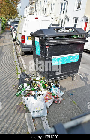 Rubbish bins overflowing with glass bottles in roadside recycling ...