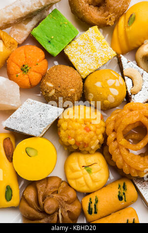 stock photo of Indian sweet or mithai and oil lamps or diya with flowers on decorative or colourful background, selective focus Stock Photo