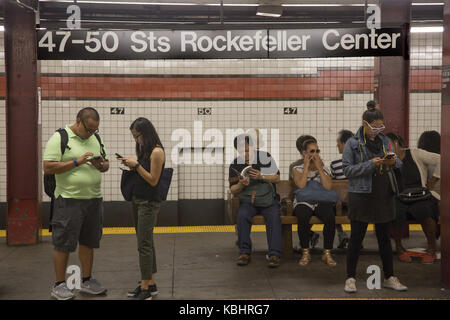 Riders study subway maps on the subway platform to figure out alternative routes due to train delays at the Rockefeller Center Station in midtown Manhattran, NYC. Stock Photo