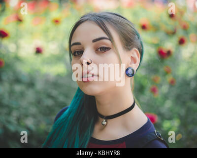 Street punk or hipster girl enjoying empty old European street. Portrait of teen girl with blue dyed hair,piercing in nose,violet lenses and unusual h Stock Photo