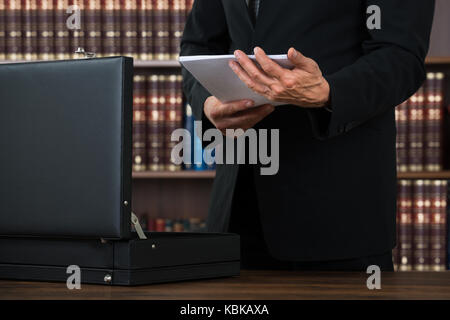 Midsection of male lawyer keeping documents in briefcase at table in office Stock Photo