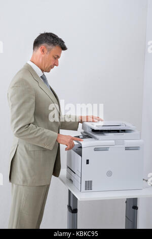 Side view of businessman keeping paper on photocopy machine in office Stock Photo