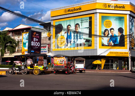Tuk tuks are parked on a city street in front of a branch office of Maybank in Kampong Cham, Cambodia. Stock Photo