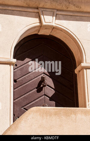 Home vintage decorations: detail of a wooden door with one door knocker in the shape of hand Stock Photo