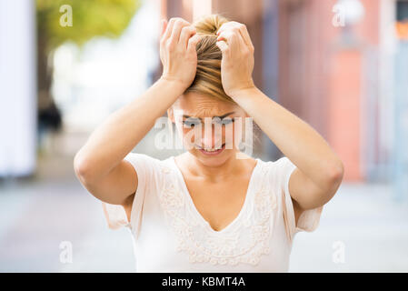 Sad young woman suffering from headache outdoors Stock Photo