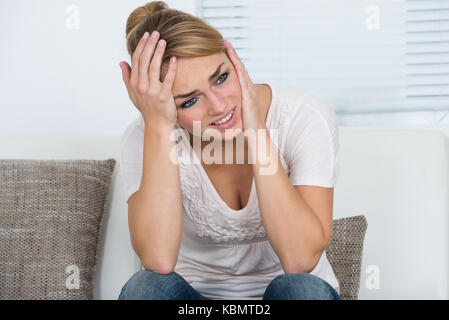 Young woman suffering from headache at home Stock Photo