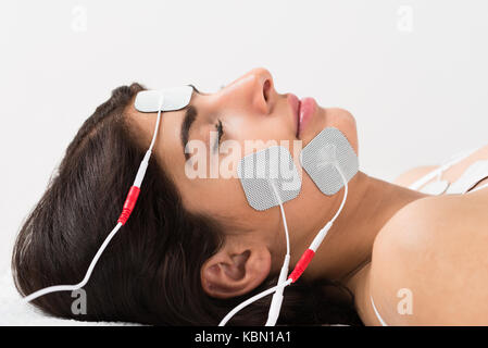 Portrait Of A Young Woman Lying With Electrodes On Her Face Stock Photo