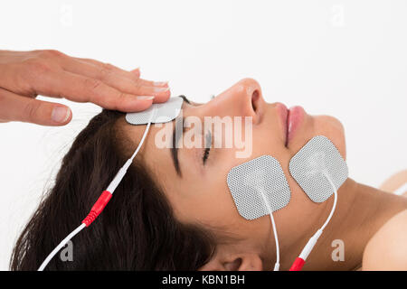 Close-up Of Hand Placing Electrodes On Young Woman's Face Stock Photo