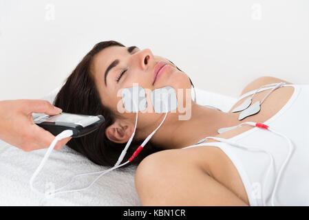 Close-up Of Therapist Giving Electrodes Therapy On Young Woman's Face Stock Photo
