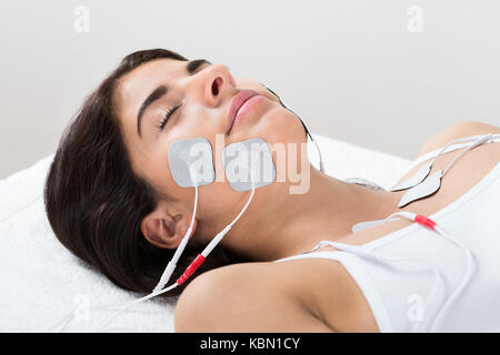 Close-up Of A Young Woman Lying With Electrodes On Her Face Stock Photo