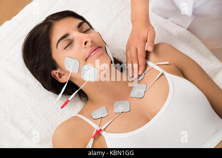 Young Woman Lying With Electrodes On Chest And Face Stock Photo