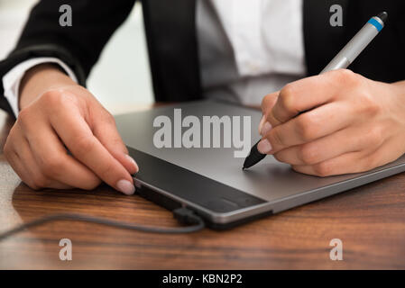 Close-up Of Person Hand Drawing On Digital Graphic Tablet With Pen Stock Photo