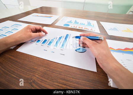 Close-up Of Businessperson Hands With Graphs At Desk Stock Photo
