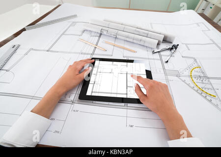 Close-up Of Architect Hands Using Digital Tablet Over Blueprint. Blueprints were created by photographer Stock Photo