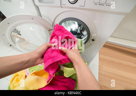 High Angle View Of Person Hands Putting Colorful Towels Into The Washing Machine Stock Photo