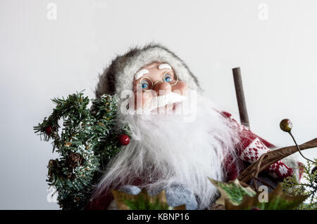 Santa Claus figure wearing glasses carrying festive branch or Christmas tree. Close up. Stock Photo