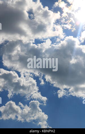 A beautiful blue afternoon sky with white clouds and the sunlight shining through. Stock Photo