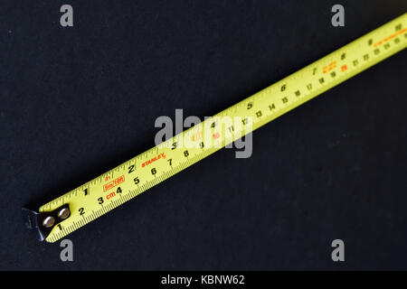 Yellow Stanley steel tape measure on black background. Stock Photo