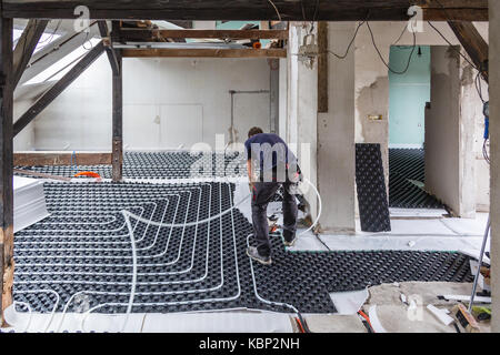 Pipe fitter mounting underfloor heating. Stock Photo