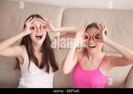 Two girlfriends being silly by making goggles with fingers. Stock Photo