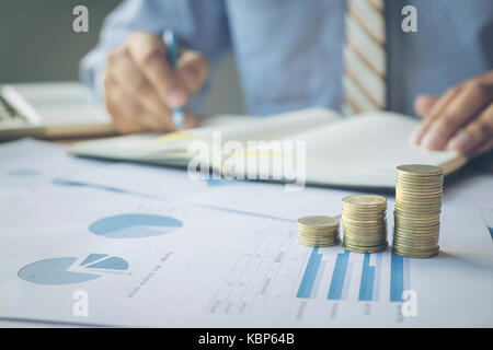 Closeup shot of blurred back ground hands counting coins and making notes on paper. Stock Photo