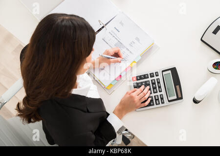 Directly above shot of young businesswoman doing financial calculation at desk in office Stock Photo