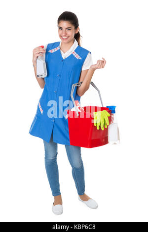 Portrait of happy female worker carrying bucket with cleaning equipment against white background Stock Photo