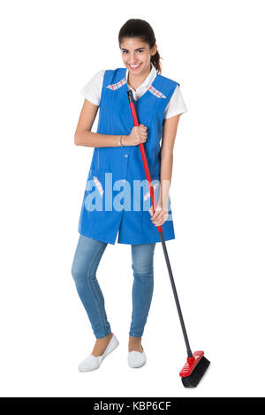 Full length portrait of happy female janitor sweeping on white background Stock Photo