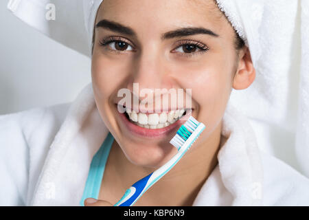 Portrait of happy young woman holding toothbrush at home Stock Photo