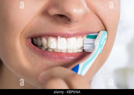 Closeup of young woman brushing teeth at home Stock Photo