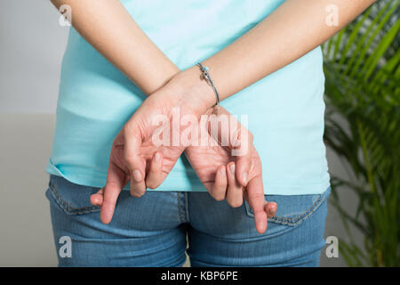 Rear view midsection of woman with fingers crossed at home
