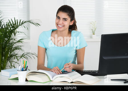 Portrait of happy female student studying at table in home office Stock Photo