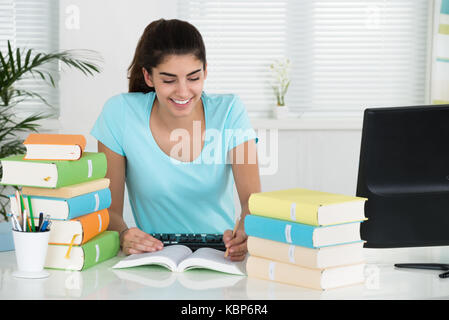 Young female student writing notes at desk in home office Stock Photo