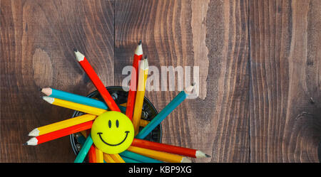Multicolored pencils in a stand on a wooden school desk  Stock Photo