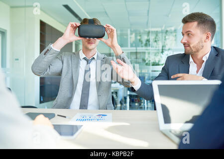 Team of creative interior designers using VR headset while working together on promising project, interior of spacious office lobby on background Stock Photo