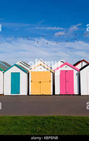 Sunny portrait shot of three colourful beach huts at Preston Sands, Paignton, Devon, UK against a mainly clear blue sky. Seafood Coast Stock Photo