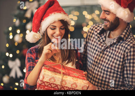 Cheerful man and woman opens Christmas gift Stock Photo