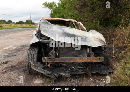 A burnt out BMW in a lay by in the UK Stock Photo