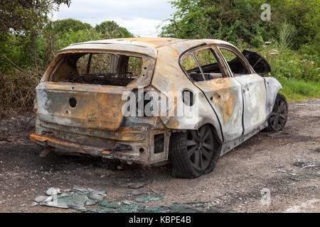 A burnt out BMW in a lay by in the UK Stock Photo