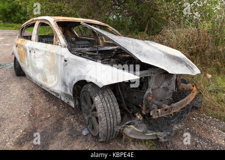 A burnt out BMW in a lay by in the UK Stock Photo