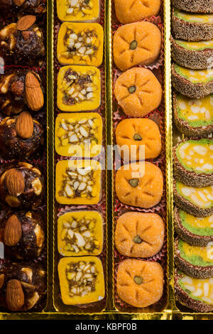 stock photo of Indian sweet or mithai and oil lamps or diya with flowers on decorative or colourful background, selective focus Stock Photo