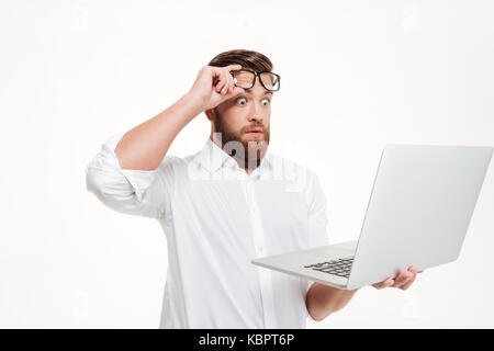 Shocked astonished man in eyeglasses looking at laptop screen isolated over white background Stock Photo