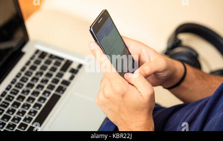 Young man looking at his smart phone, closeup on the hands Stock Photo