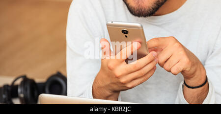Young man looking at his smart phone, closeup on the hands Stock Photo